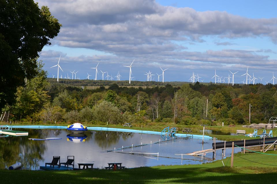 The Ponderosa pond and swimming beach with an inflatable water playground, wind turbines on the far horizon.
